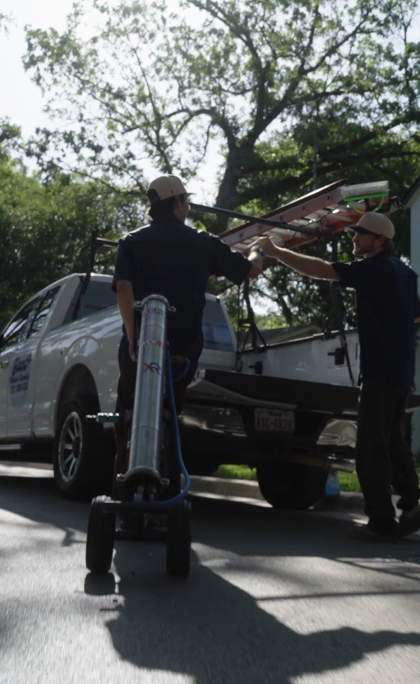 Giant Window Cleaning crew setting up a ladder and water-fed filtration equipment beside the service truck