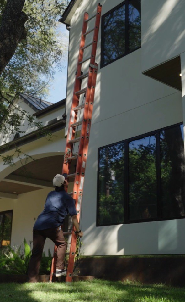 Giant Window Cleaning technician positioning a ladder at tall residential windows