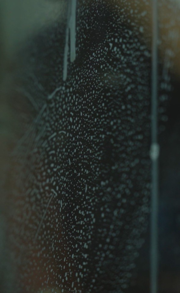 Close view of soapy water across a window before the finishing pass