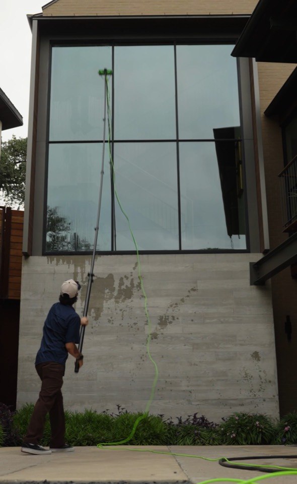 Giant Window Cleaning technician using a water-fed pole on a tall wall of exterior glass